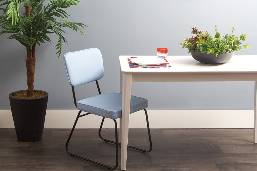 ambiente com cadeira de couro lucy azul visto na diagonal com mesa de jantar
