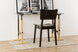 ambiente com cadeira de madeira uma preta vista de tras em frente de uma escrivaninha com quadros sobre ela