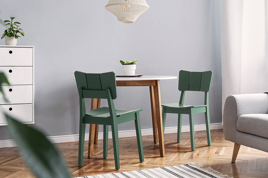 foto ambientada com cadeira para mesa de jantar uma verde escuro ao redor de uma mesa redonda