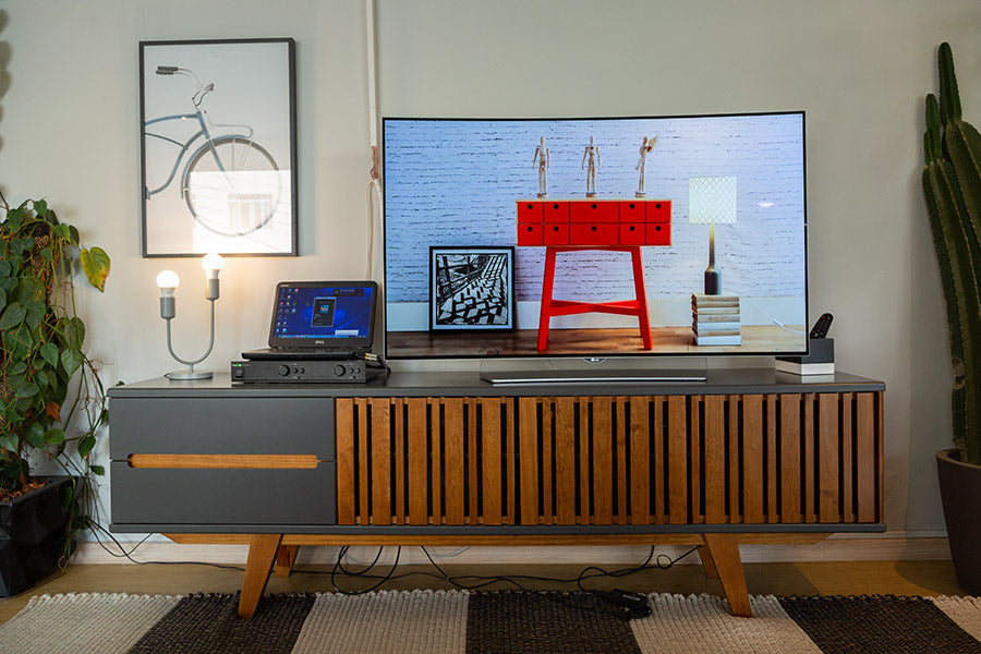 foto ambientada de sala de estar com rack para sala de tv panteon grafite visto de frente com objetos sobre rack