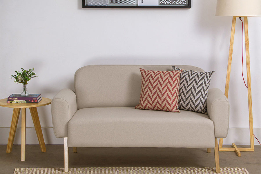 foto ambientada sofa dois lugares agnes cru ao lado de uma mesa lateral com uma mesa lateral cru e uma almofada vermelha